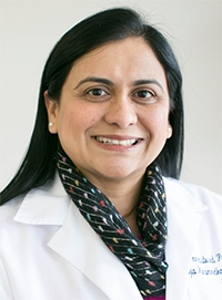 The image features a woman wearing a white lab coat, smiling at the camera, with a name tag visible, set against a plain background.